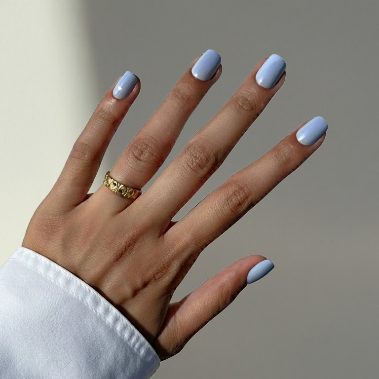 Hand with light blue nail polish on a neutral background